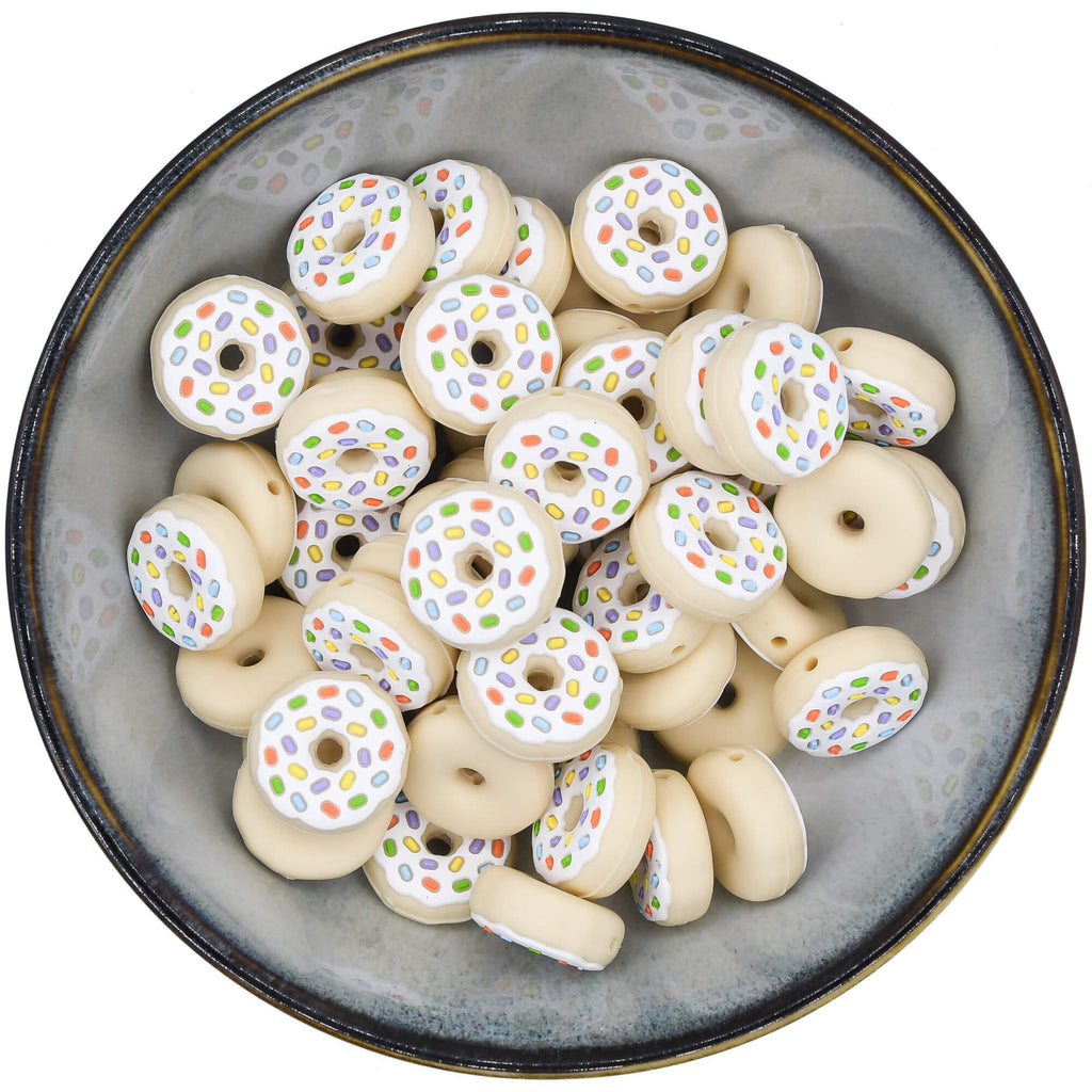 Siliconen figuurkraal in de vorm van een donut met wit glazuur en groen, oranje, paars, blauw en gele spikkels